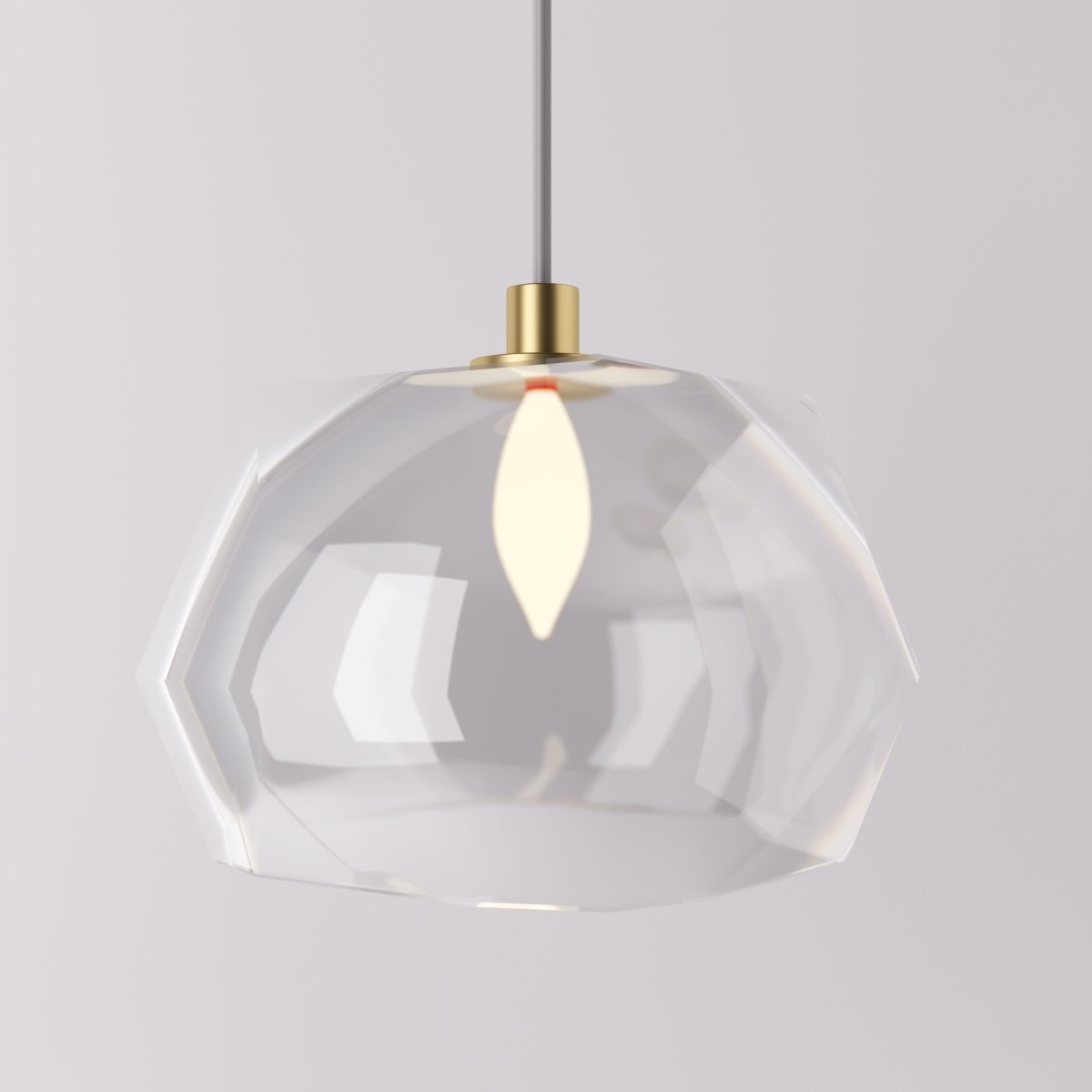 Clérachic pendant light faceted glass shade lit warm, its angled clear panels on a brass cord fitting.