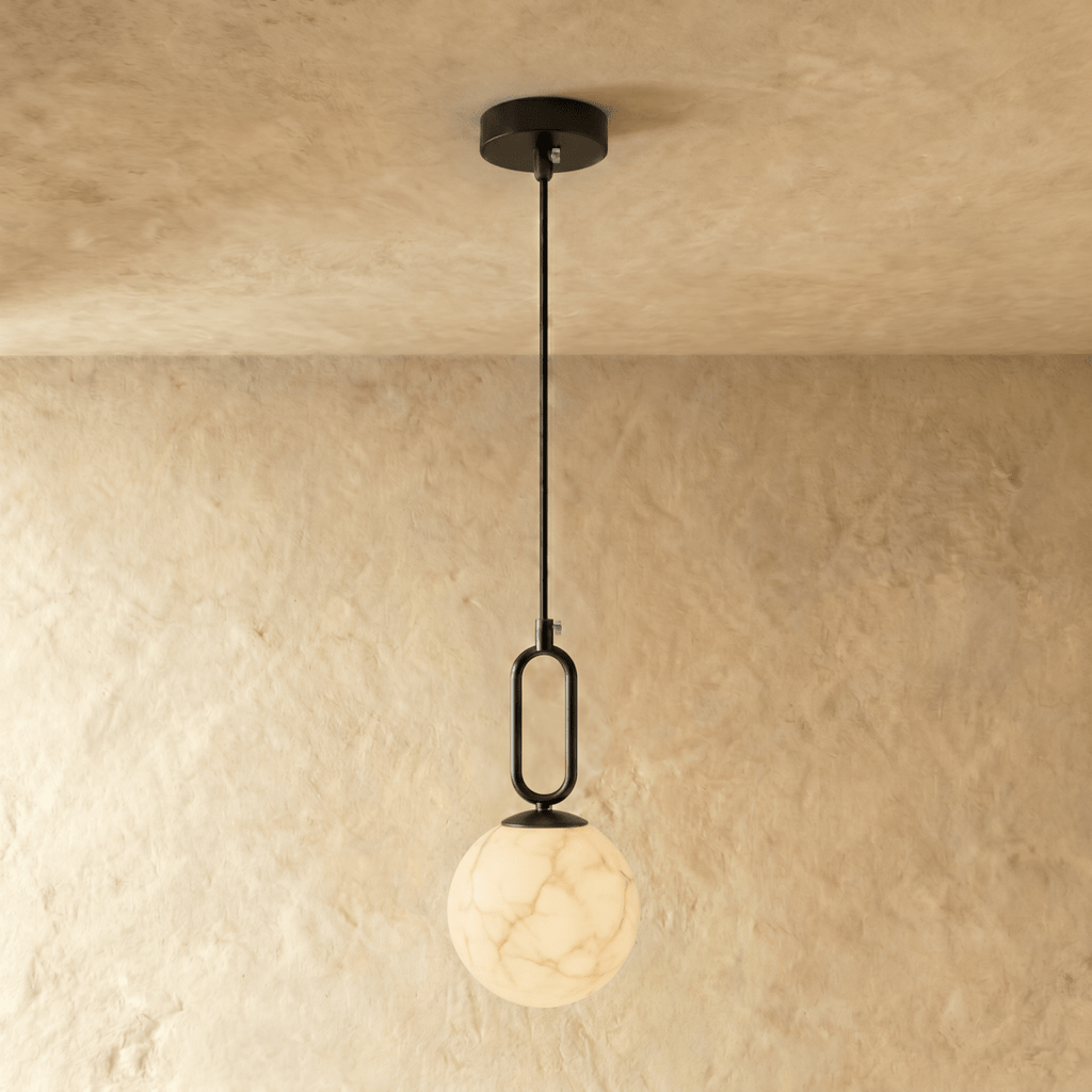 Clérachic black-hardware pendant light with a round alabaster globe, hung low on a slim rod from the ceiling.