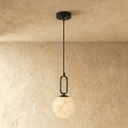 Clérachic black-hardware pendant light with a round alabaster globe, hung low on a slim rod from the ceiling.