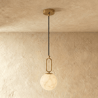 Clérachic gold pendant light with a round alabaster globe, its oval link hardware catching light near a wall.