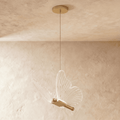 Clérachic brass butterfly pendant light with clear ribbed wings, hanging from a slim cord against a plaster ceiling.