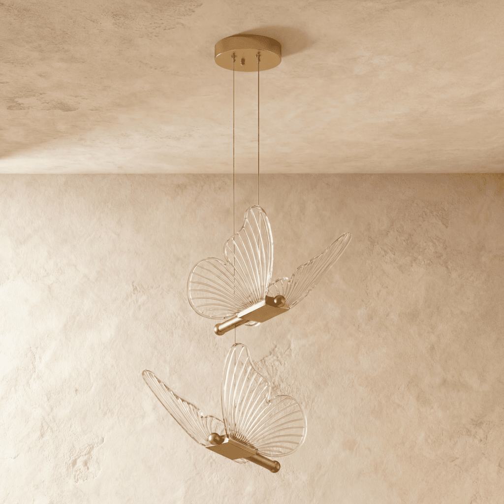 Clérachic brass double-head butterfly pendant light, two clear wing fixtures suspended at different heights.