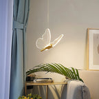 Clérachic brass butterfly pendant light glowing warm white above a round gold side table in a living room.