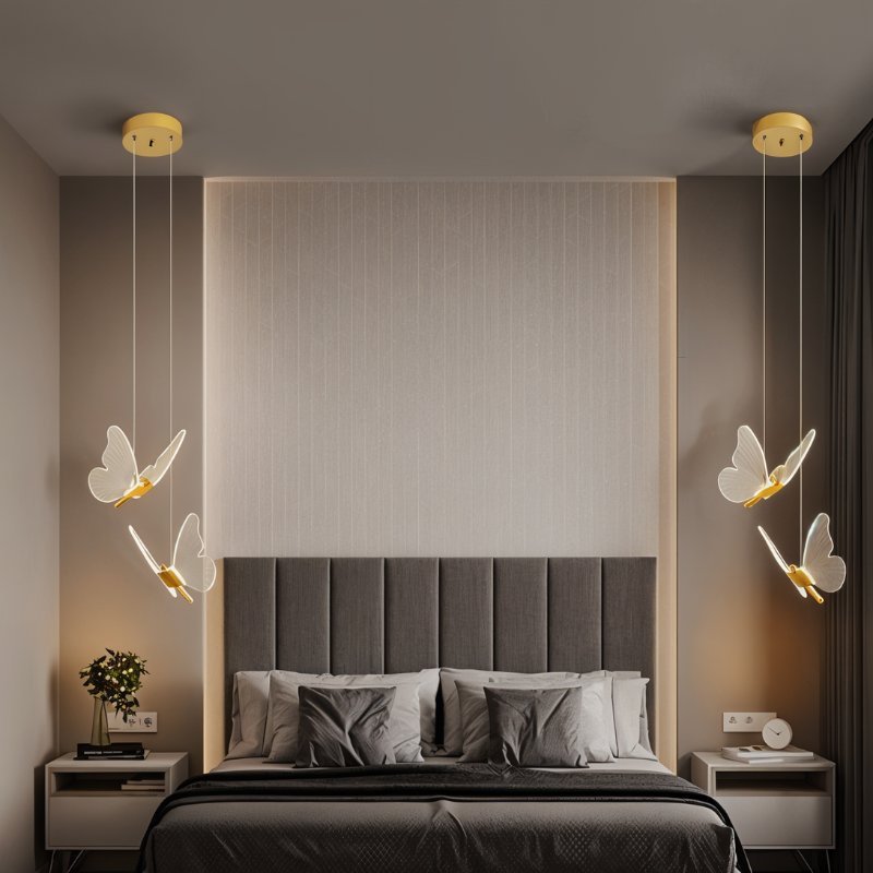 Clérachic brass double-head butterfly pendant lights flanking an upholstered headboard in a neutral bedroom.