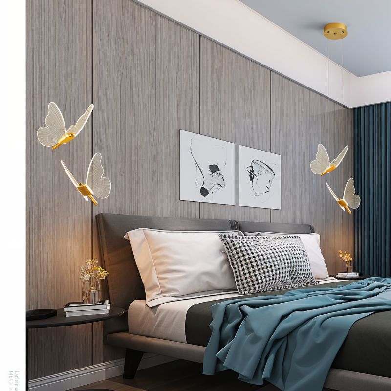 Clérachic brass double-head butterfly pendant lights flanking a wood-paneled wall above a grey upholstered bed.