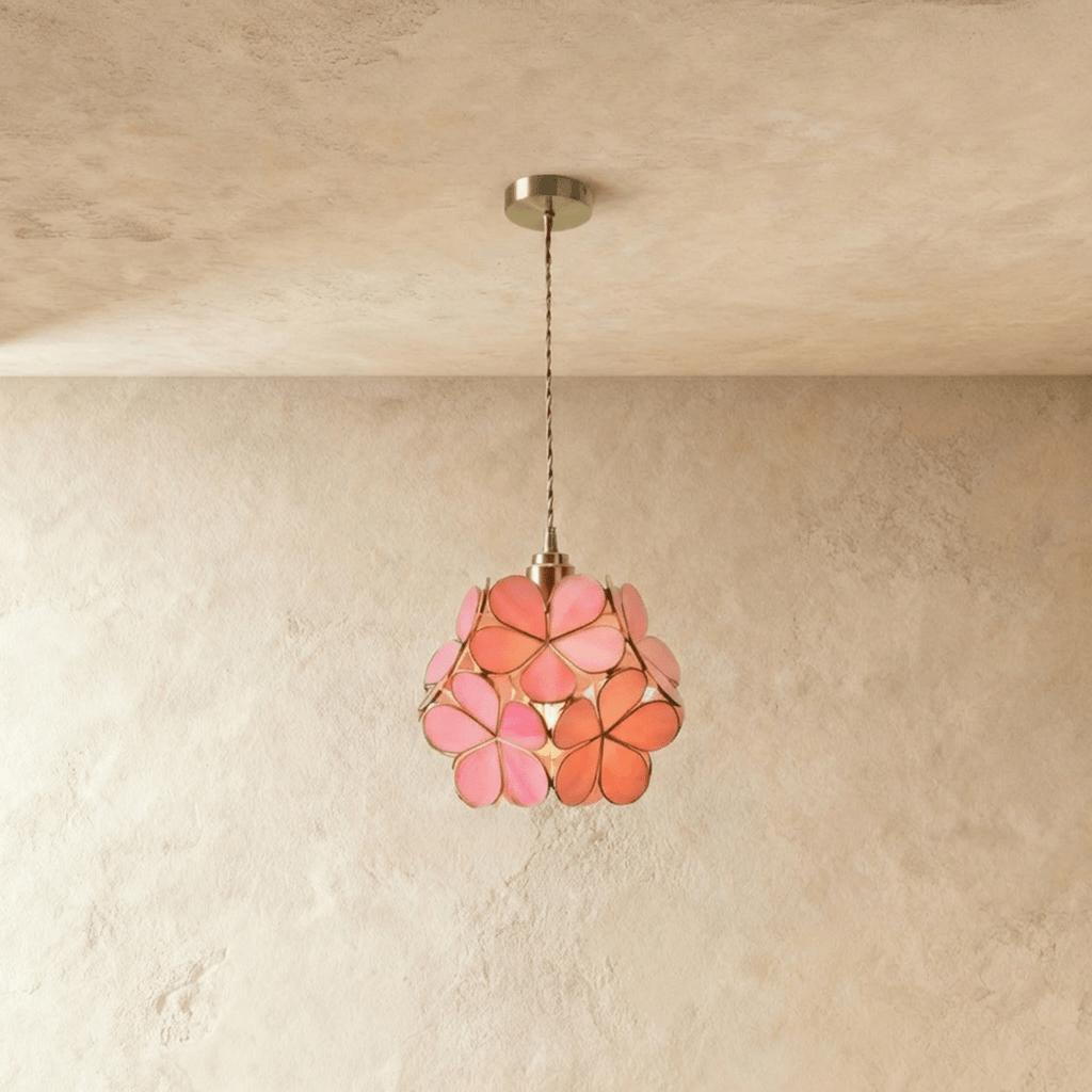 Clérachic single pendant of pink and coral glass petals edged in brass, hung on a twisted cord against limewash.