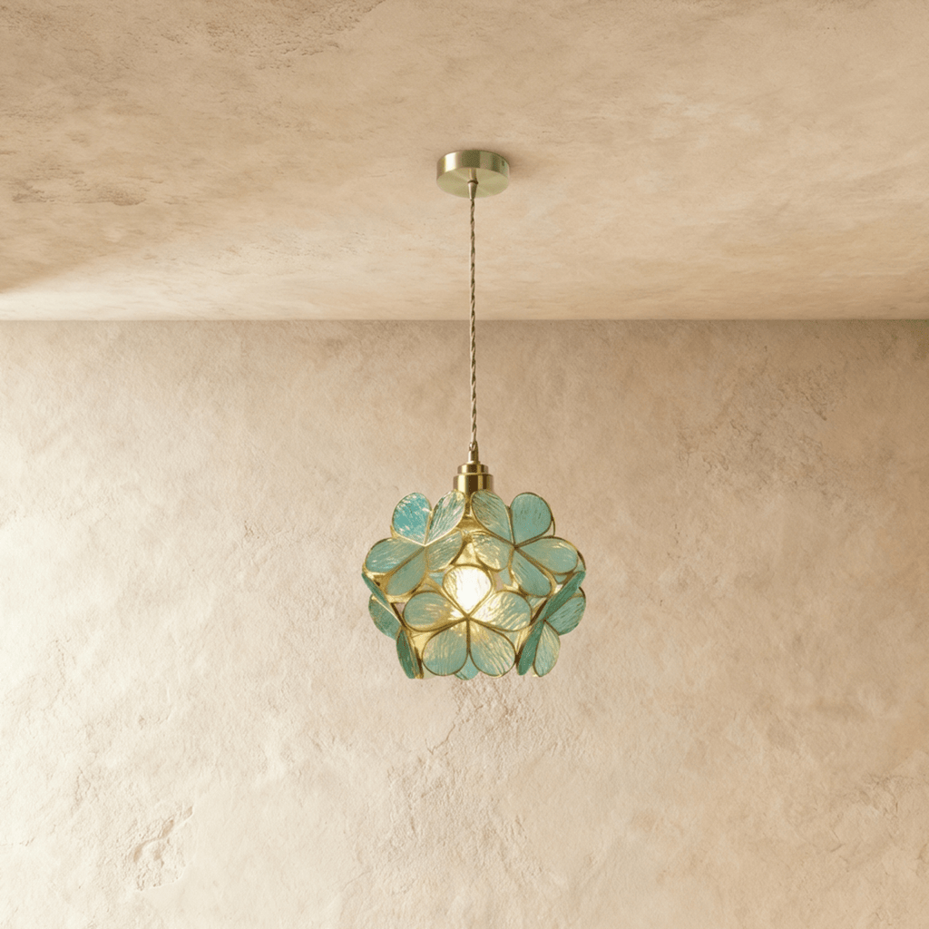 Clérachic single pendant of textured blue-green glass petals edged in brass, hung on a twisted cord against limewash.