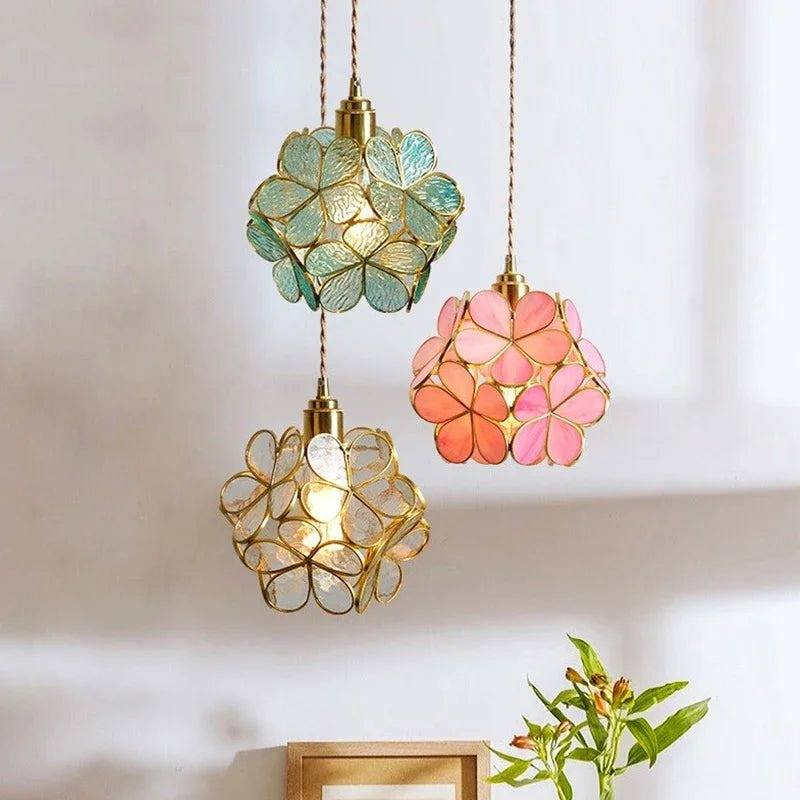 Clérachic trio of glass petal pendants in blue-green, pink and clear on brass fittings, hung at different heights.