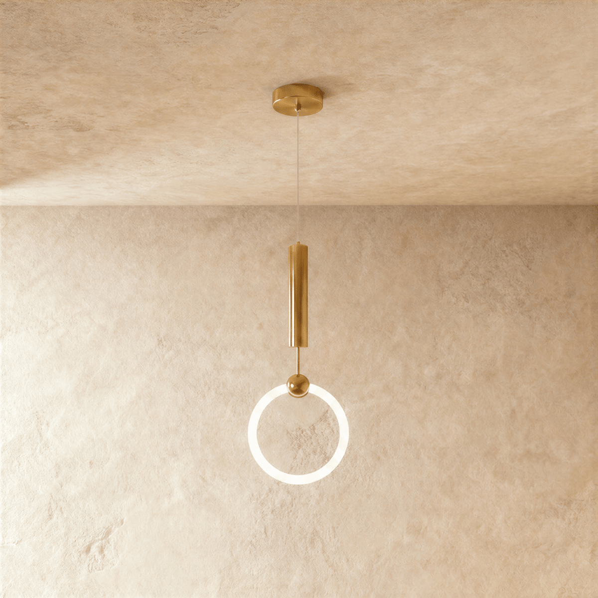 Clérachic gold pendant with a glowing opal ring held by a brass stem and small ball, hung on a fine wire against plaster.