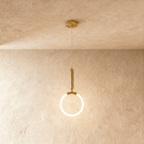 Clérachic gold pendant with a glowing opal ring and a rounded brass handle above, hanging from a ceiling plate on wire.