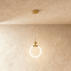 Clérachic gold pendant with a glowing opal ring, small brass ball and thin rod, hung from a round canopy on fine wire.