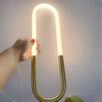 Clérachic hand holding a lit opal U-shaped tube above a brass base, with a gold round plate at the lower edge.