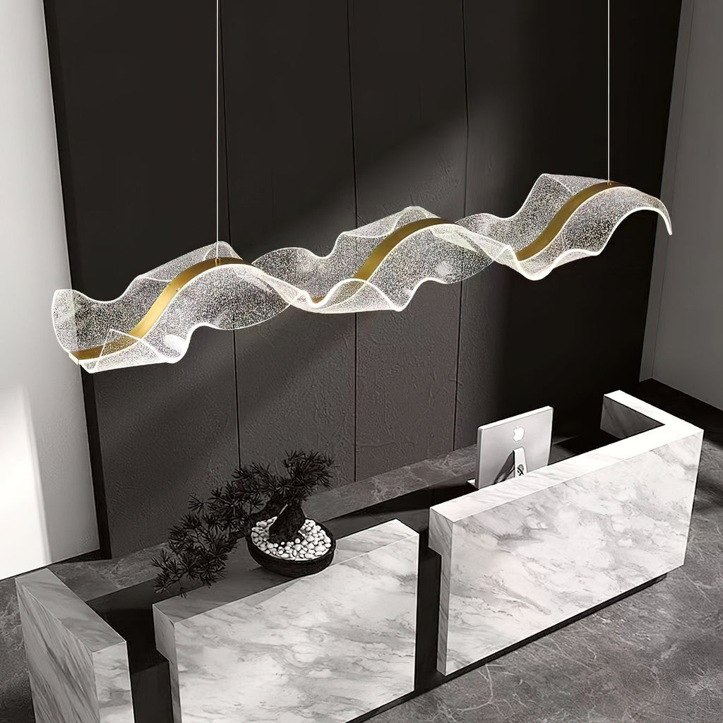 Close angle on this Clérachic pendant, its textured clear acrylic wave and gold strip hanging above a white marble reception desk.