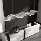 Close angle on this Clérachic pendant, its textured clear acrylic wave and gold strip hanging above a white marble reception desk.