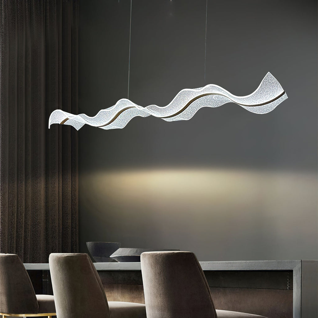 Side view of this Clérachic pendant over dark upholstered dining chairs, a warm pool of light falling on the grey wall behind.