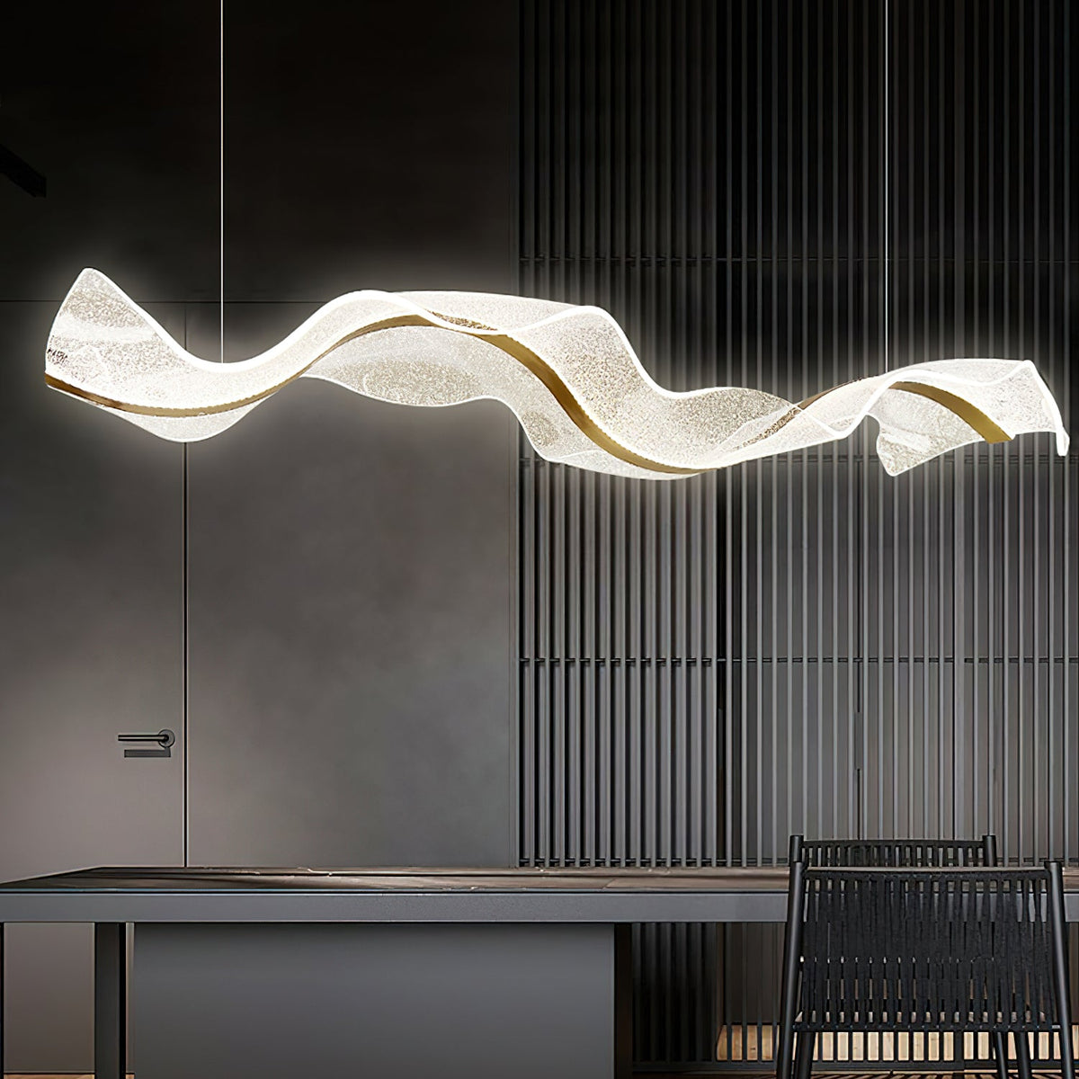 This Clérachic pendant lit against a charcoal slatted wall, its white wave shape glowing over a dark table with a woven chair.