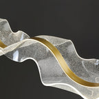Close view of the bubble-textured clear acrylic and the curved gold band on this Clérachic pendant, against a black background.