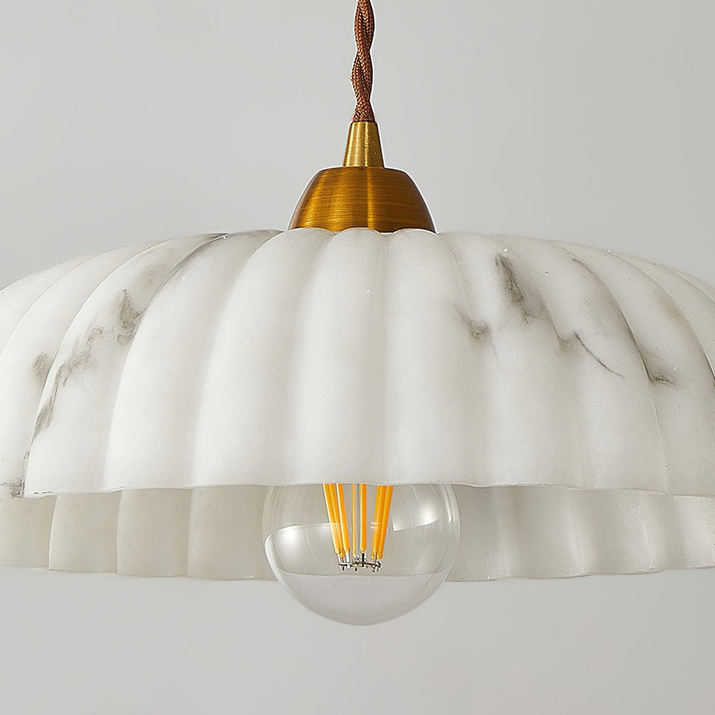 Close view of the scalloped rim and filament bulb of this Clérachic pendant, with soft grey veining running through the shade.