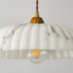 Close view of the scalloped rim and filament bulb of this Clérachic pendant, with soft grey veining running through the shade.