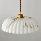 Side view of the wide, ribbed white shade with grey veining on this Clérachic pendant, with a gold cap and twisted brown cord.