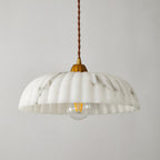 A Clérachic pendant with a shallow ribbed white shade, a gold cap and a visible filament bulb, on a light grey backdrop.