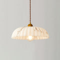 Lit Clérachic pendant with a veined, scalloped white shade and a twisted brown cord, on a soft grey backdrop.