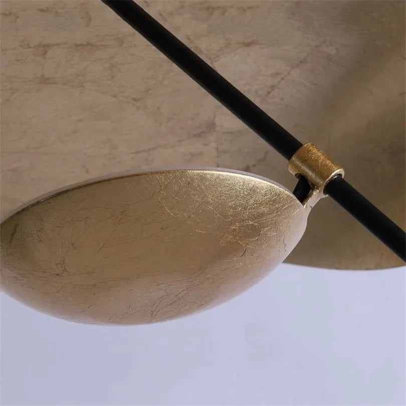 Macro view of the gold-leaf lining inside the Clérachic pendant light's shade, with its brass cord clip in focus.