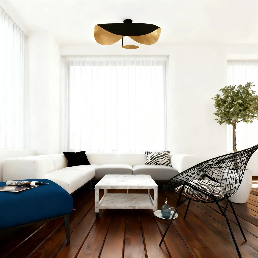 The black-and-gold Clérachic pendant light flush-mounted above a doorway between a white sectional and blue ottoman.
