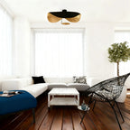 The black-and-gold Clérachic pendant light flush-mounted above a doorway between a white sectional and blue ottoman.