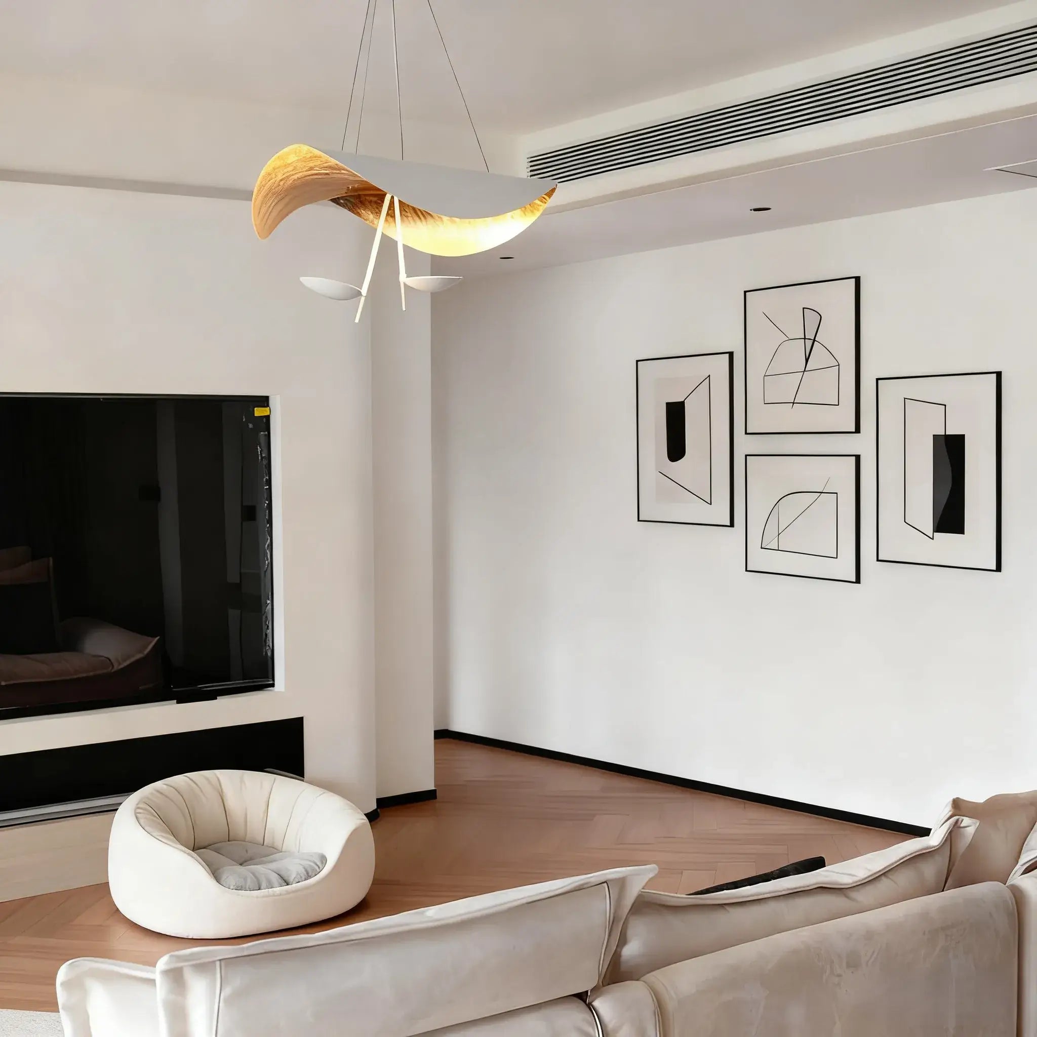 A gold-lit Clérachic pendant light glows above a minimalist living room hung with framed abstract line art.