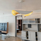 The gold-and-grey Clérachic pendant light glowing above a doorway between open shelving in a grey-toned living room.
