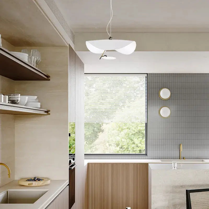 The white Clérachic pendant light hangs by a kitchen window, with matching round wall sconces on the tiled backsplash.