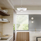 The white Clérachic pendant light hangs by a kitchen window, with matching round wall sconces on the tiled backsplash.