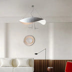 A pale Clérachic pendant light centred in a warm living room, near a round wall light and a black arc floor lamp.