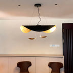 The black-and-gold Clérachic pendant light glowing above an entryway console beside a dark wood door and switch plate.