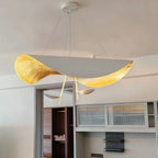 Wide view of the white-and-gold Clérachic pendant light glowing above open-plan cabinetry and a bedroom doorway.
