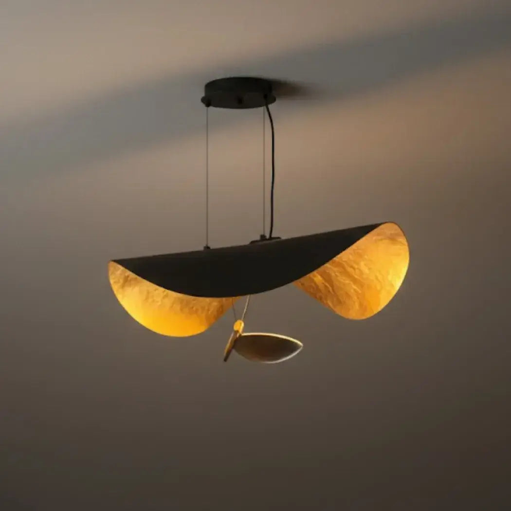 Studio shot of the Clérachic pendant light in black and gold, one accent disc dropped low while the second stem sits bare.