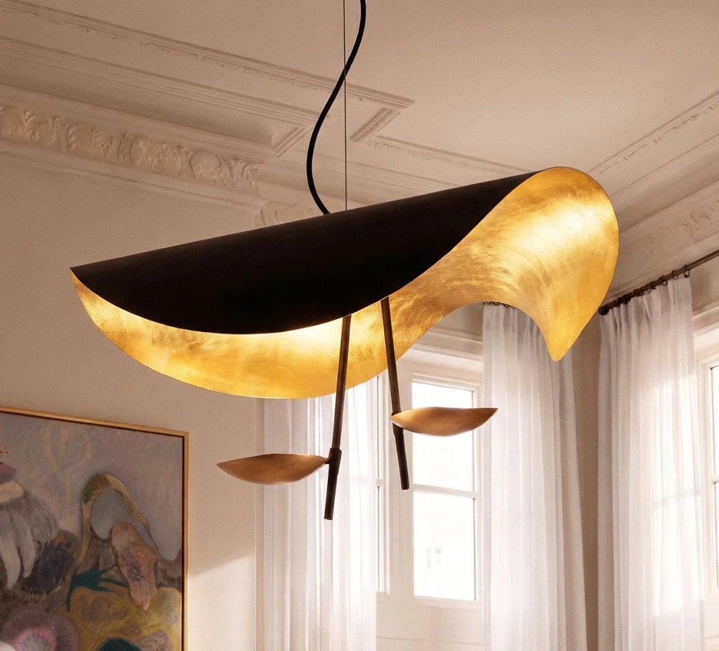 Close view of the Clérachic black pendant: curled shade with glowing gold-leaf lining and two bronze-toned discs on dark slim arms