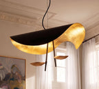 Close view of the Clérachic black pendant: curled shade with glowing gold-leaf lining and two bronze-toned discs on dark slim arms