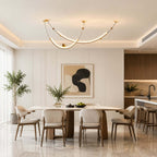 Lit Clérachic pendant over a pale oval dining table, with an abstract print on the wall and an olive tree in the corner.