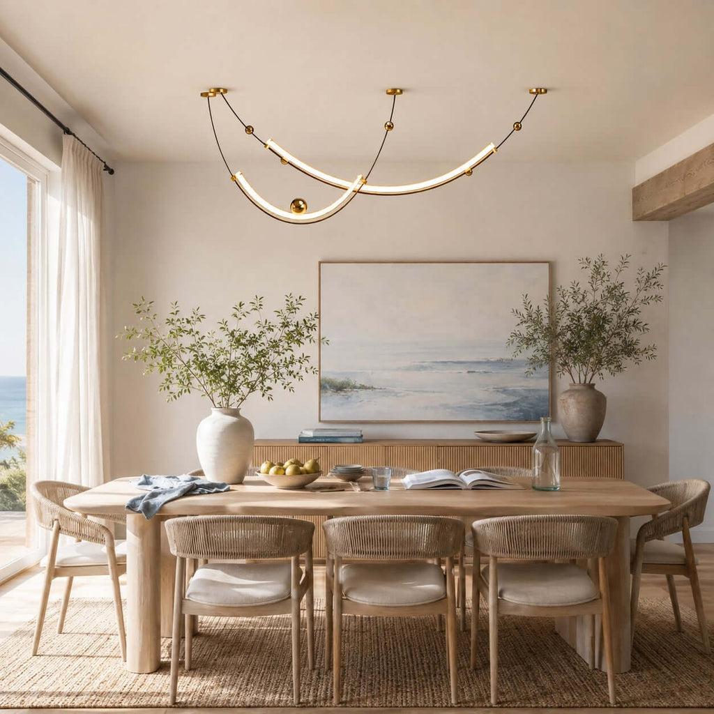 Clérachic pendant above a light oak dining table and rattan chairs, with a seascape painting and a jute rug beneath.