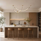 Clérachic pendant centred above a pale stone kitchen island with three wooden stools, light oak cabinets behind.