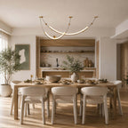 Clérachic pendant above a set dining table with six cream chairs, a green framed print and open shelves behind.