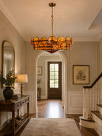 Amber chandelier from Clérachic hanging in a hallway beneath an arched opening, with a console table, a table lamp and a front door beyond.