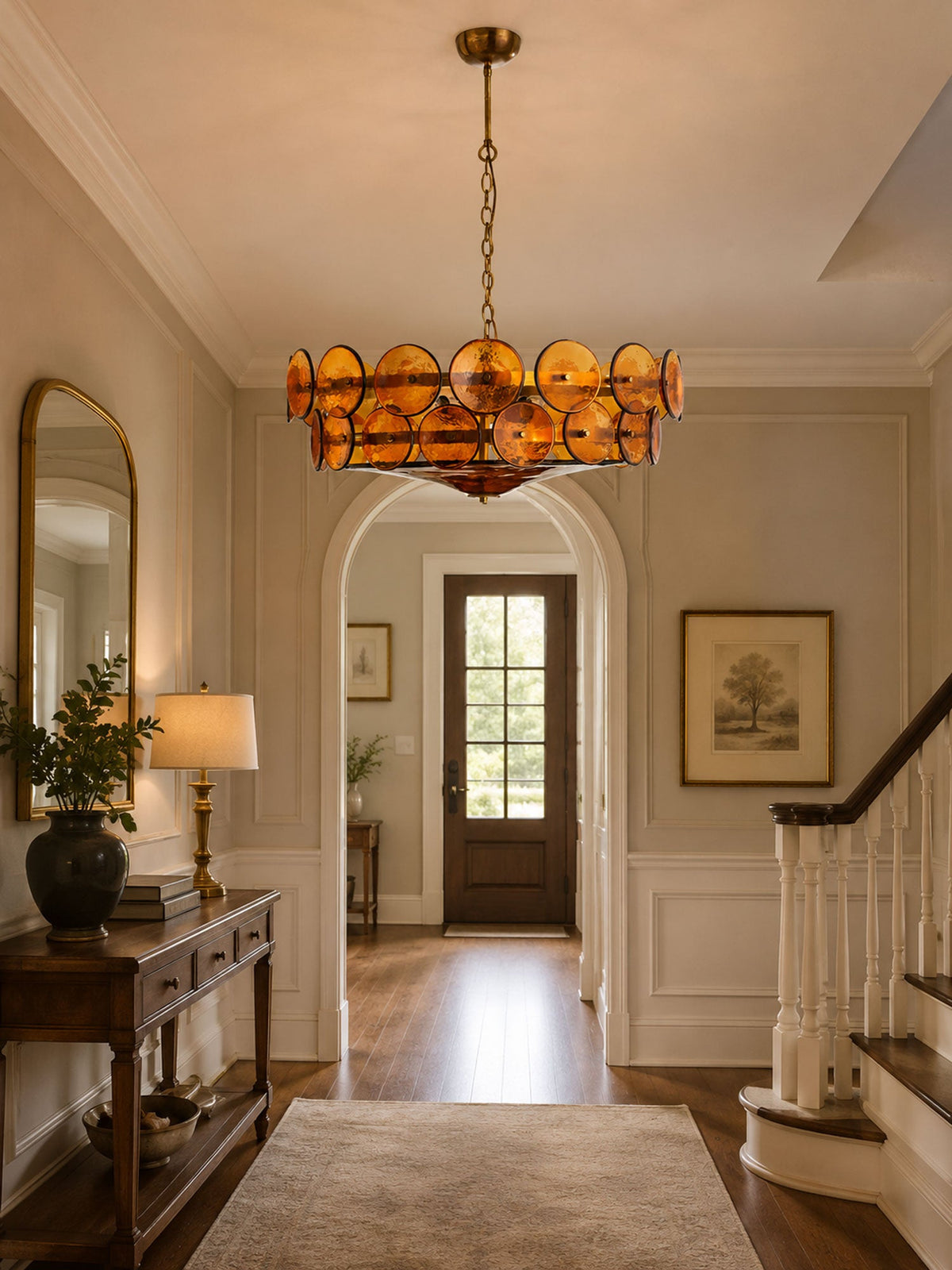 Amber chandelier from Clérachic hanging in a hallway beneath an arched opening, with a console table, a table lamp and a front door beyond.