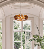 Amber glass disc chandelier from Clérachic framed by a tall arched window and a domed plaster ceiling, with treetops outside.