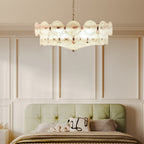 Close view of a white frosted disc chandelier above a sage-green upholstered headboard and panelled wall, a Clérachic bedroom light.