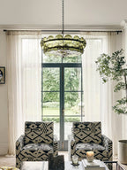 Green glass discs ring this Clérachic chandelier above two patterned armchairs, in front of French doors and sheer curtains.