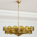 Full view of a green and gold Clérachic chandelier on its long gold chain and domed ceiling canopy, against white cornice mouldings.