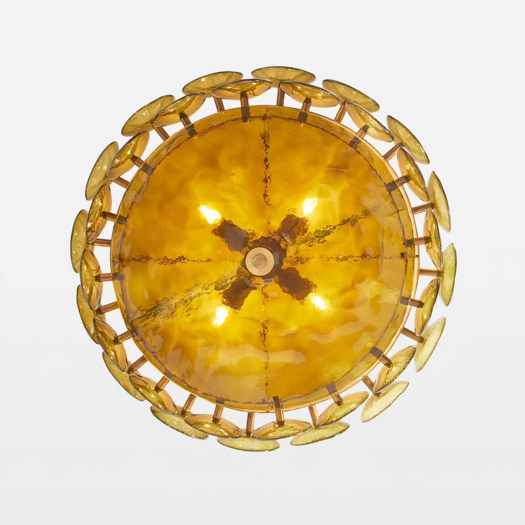 Looking up at the underside of this Clérachic chandelier, a glowing amber bowl ringed by overlapping gold-green glass discs.